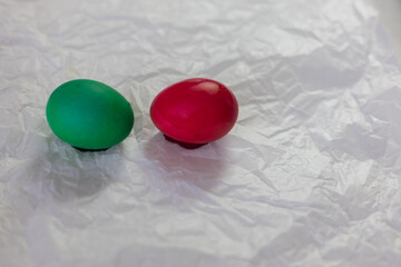 Brightly colored Easter eggs – various colors - green, yellow, red, blue – arranged on crumpled white paper. The eggs are smooth and shiny, ready for decoration or display at Easter