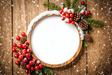 Rustic christmas wreath frame with berries and pine cones on wood