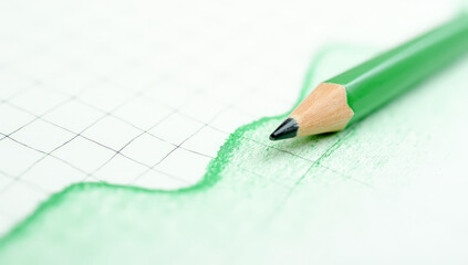 A green pencil draws a trading chart, close-up