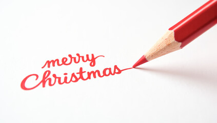 A red pencil writes merry Christmas on paper