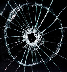 Large Circular Hole in Shattered Glass with Radial Cracking on Black Background