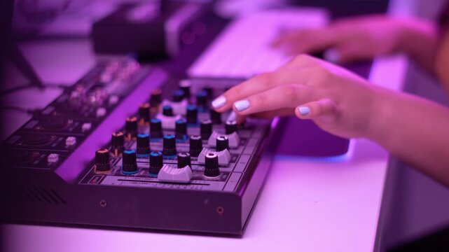 A hand touches mixer sliders while soft glowing lights highlight the textures and motion of the equipment.