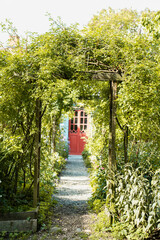 alte rote T&uuml;r in einem verwachsenen Garten 