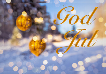 "God Jul" means "Merry Christmas" in Swedish and Norwegian. Blurred background of beautiful Christmas tree in snow decorated with big golden balls. Bokeh Forest Snow. Happy New Year! Sweden Norway.