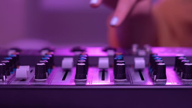 Fingers rotate mixer controls while vibrant lighting fills the workspace, highlighting motion and precision.