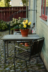 gem&uuml;tliche Sitzecke mit gelben Blumen im Garten vor einem Holzhaus