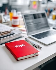 Bright Red Notebook on Desk with Laptop, Pens, and Colorful Office Supplies in Background