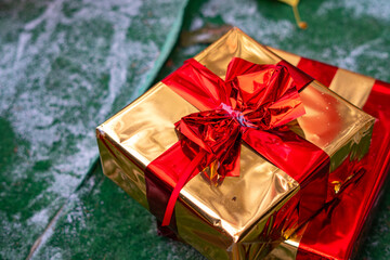 Gold gift box with a red bow resting on a green surface creates a striking festive decoration at the Christmas market