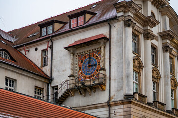 Fototapeta premium Historic mosaic façade clock on a classical building in central Poznań, framed by columns and a red tiled roof