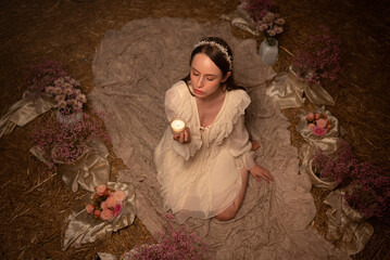Woman in Floral Ritual Setting Holding a Candle &mdash; Top View