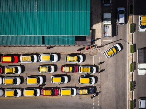 Aerial view of yellow taxis lined up beneath a green roof, their vibrant colors contrasting against the dull asphalt, Thimphu, Bhutan.