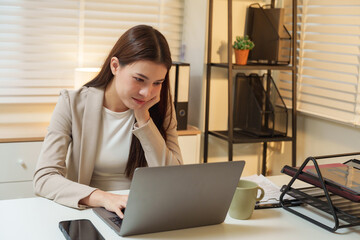 Concentrated asian businesswoman working late on laptop in cozy office environment symbol of productivity determination and modern corporate lifestyle professional career dedication