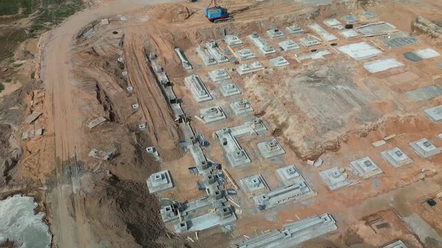 Explore the construction site with an aerial look at various reinforced concrete foundations being laid for a new structure in a busy area.