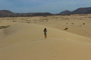 European woman walking through Corralejo sand dunes on a sunny day