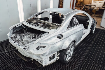 Fototapeta premium Professional car painting in a specialized spray booth at an auto service center. Body repair and surface preparation process. Quality maintenance and technical service for modern vehicle transport.