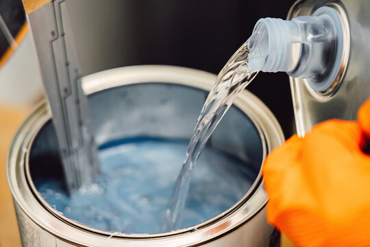 Careful mixing and measuring of automotive paint in a can for precise color matching. Chemistry and technical preparation for high quality body repair and professional painting service maintenance.