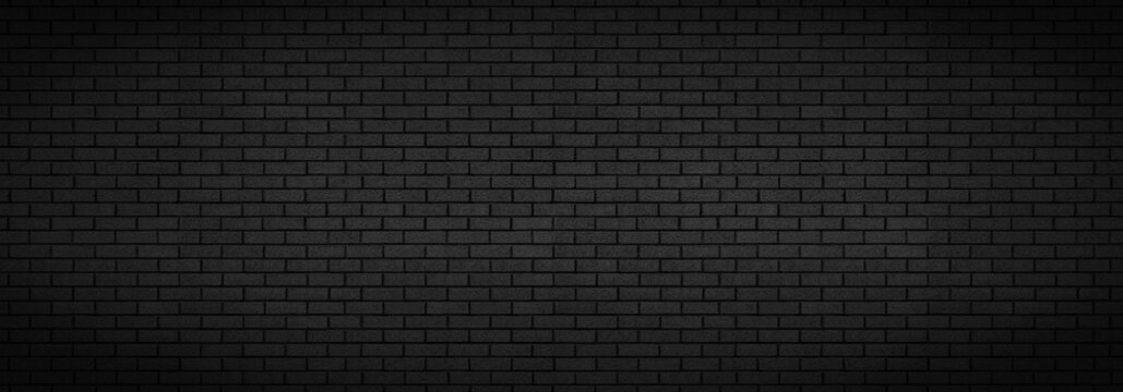 Black brick wall background texture. Dark panoramic night time city or town building design backdrop. Copy room for text.