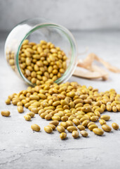 Creamy yellow Mayocoba beans pour from a glass jar, spreading across a stone surface. Heirloom legumes, seed germination, plant growth, healthy cooking ingredients, and natural food staples concept. 