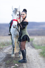Charming European lady posing with a majestic white horse in an open field, symbolizing freedom, calmness, and connection with nature.