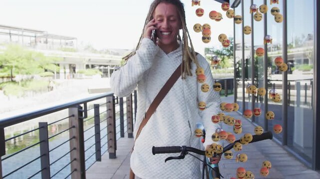 Man walking pushing bike using phone, phone call starting social emoji cloud on waterfront by glass