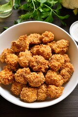 Breaded oven baked cauliflower bites in bowl on wooden table