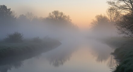 Fototapeta premium Serene river winds through a heavily fogged natural landscape at dawn