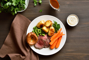 Sunday roast with roasted beef, carrots, crispy potato, green pea and yorkshire pudding.