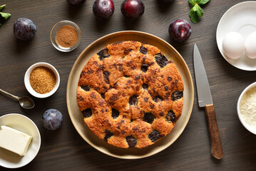 Homemade plum pie on plate on wooden table