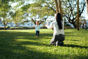 Fototapeta premium Baby taking first steps towards mother in park
