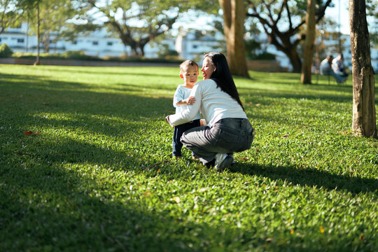 Mother bonding with young son in park enjoying sunny day