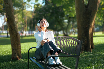 Young woman enjoying music and relaxing in park