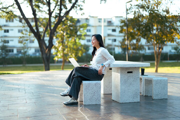 Young woman remote working outdoors with laptop in park