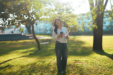 Young woman walking campus park during sunny day