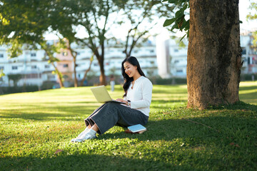 Young Asian woman working on laptop outdoors