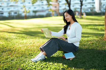 Young woman remote working on laptop in park
