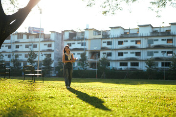 Young Asian female student walking across campus park