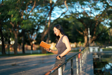Woman enjoying reading book outdoors in park setting