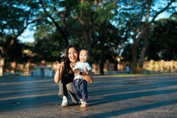 Asian mother and toddler son smiling in park