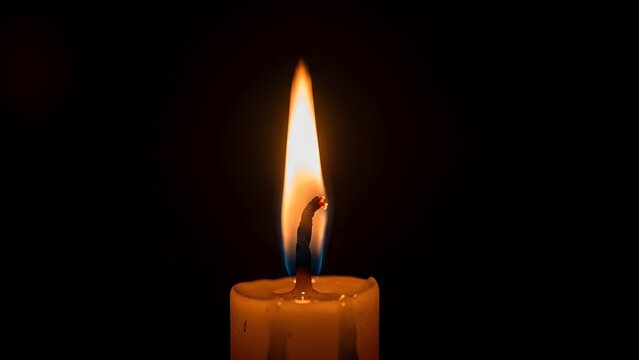 Close up of a candle flame against a dark black background