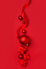 An abstract and artistic arrangement of red Christmas ornaments and ribbons on a solid red background.