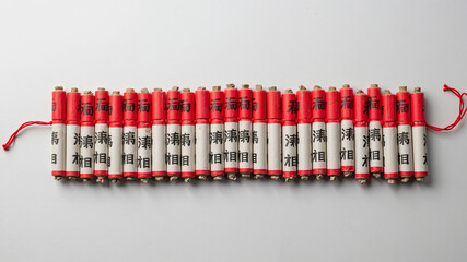 Firecrackers on string arranged in a flat row on a white surface  