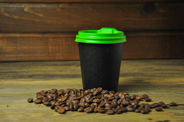 coffee beans and a disposable glass with a lid for hot drinks on a wooden table