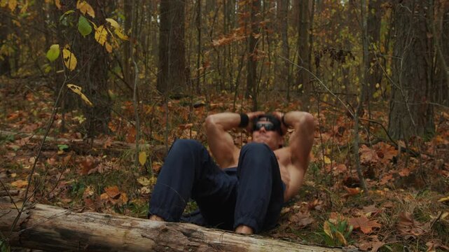 Shirtless bodybuilder training in an autumn forest
