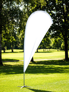 Blank white teardrop flag mockup on grass outdoor front view centered flat fabric empty copy space beach event advertising sign display branding design presentation template