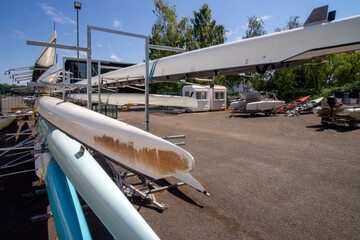 Rowing boats stored on outdoor racking systems at Watersports Centre at Strathclyde Country Park Scotland. UK. The boats are long, narrow, and lightweight vessels for the sport of competitive rowing. 