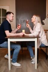Romantic evening with wine, candles in homely setting. Couple enjoys warm atmosphere of dinner, holding hands, gazing lovingly at each other with glass of wine. Romantic date concept, Valentine's Day