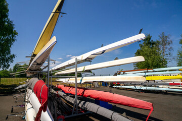 Rowing boats stored on outdoor racking systems at Watersports Centre at Strathclyde Country Park Scotland. UK. The boats are long, narrow, and lightweight vessels for the sport of competitive rowing. 