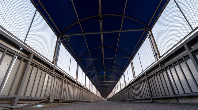 Long Pedestrian Overpass with Blue Roof and Metal Railings