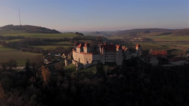 Drone image of Harburg Castle on its mountain spur overlooking Harburg city and the Woernitz Valley in Bavaria, Germany under soft golden evening light.