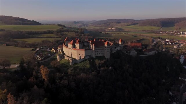 Aerial drone view of Burg Harburg on the mountain spur above the Woernitz River in Harburg, Bavaria, Germany showing the medieval castle complex at sunset in cold autumn weather.